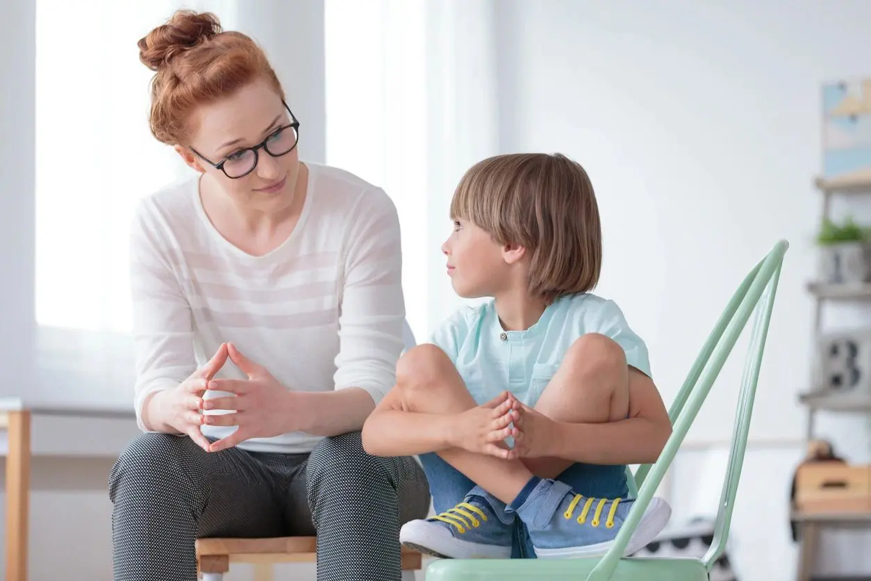A woman attentively listens to a young boy sitting cross-legged.